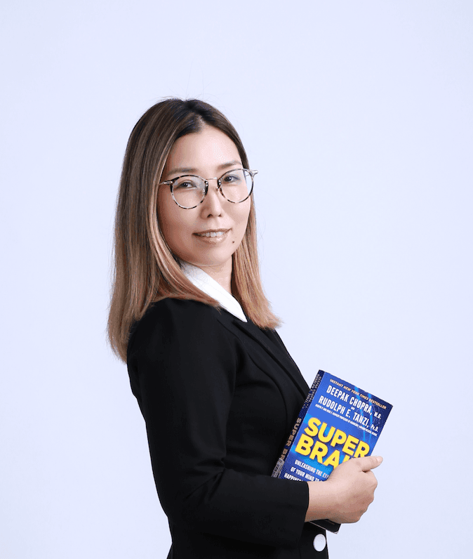 Person in a suit holding a book titled 'Super Brain' against a light background.